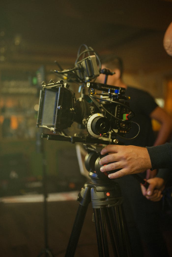 Close-up of a filmmaker operating a professional video camera setup indoors.
